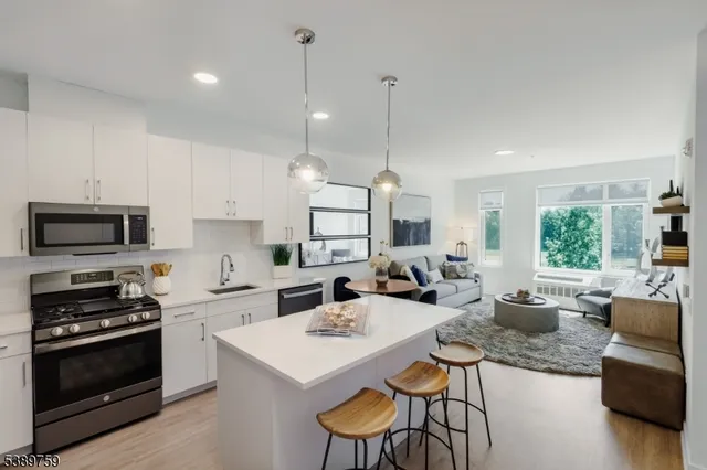 a kitchen with stainless steel appliances kitchen island granite countertop a stove a sink a microwave a dining table and chairs