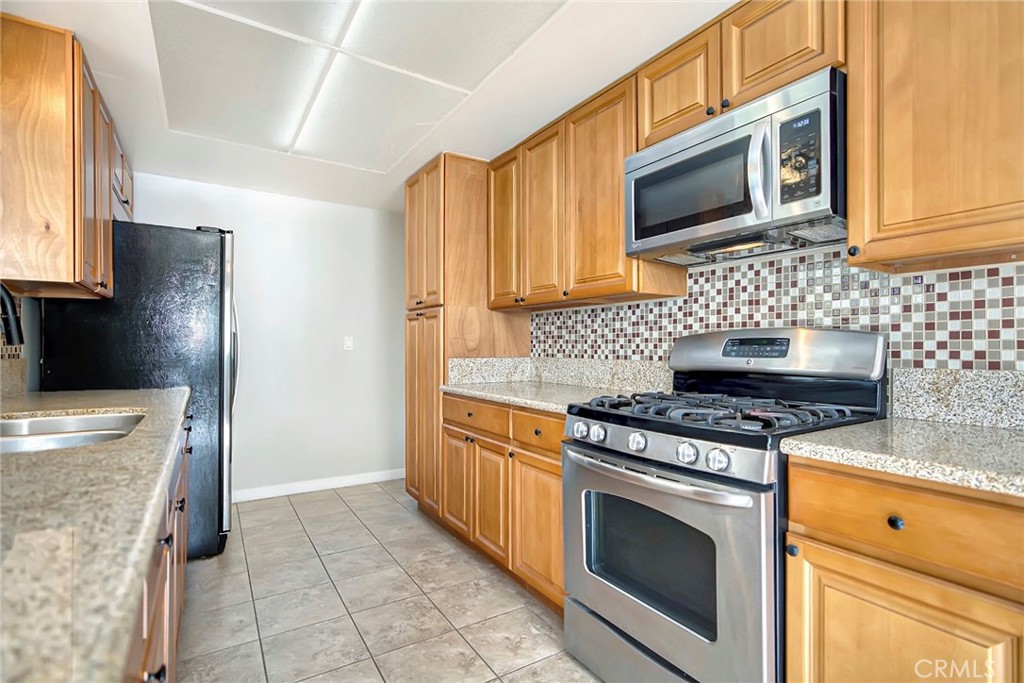 1115 South Groveland Place Anaheim, CA 92806 - Photo 20 of 42 a kitchen with granite countertop a stove top oven microwave and cabinets