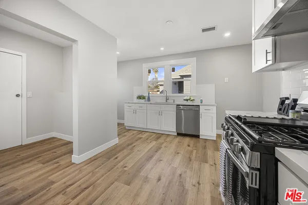 a kitchen with a stove a sink and wooden floor