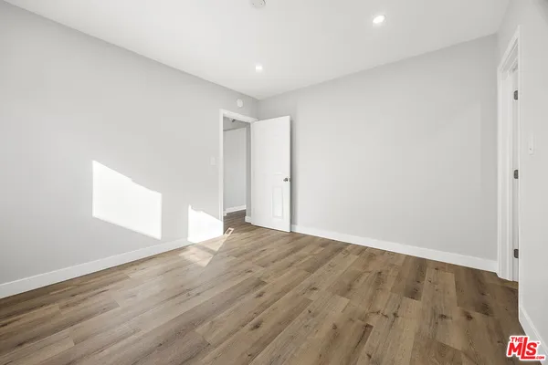 a view of an empty room with wooden floor and window