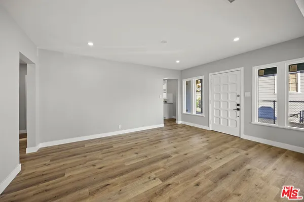a view of empty room with wooden floor and entryway