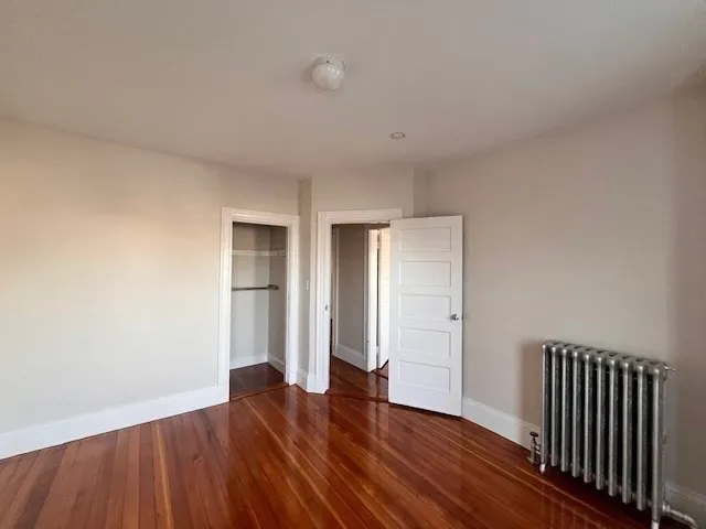 an empty room with wooden floor & windows