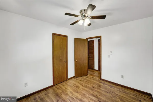 an empty room with wooden floor closet and ceiling fan