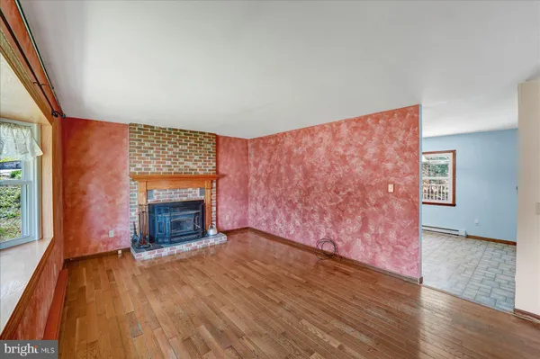 an empty room with wooden floor fireplace and windows