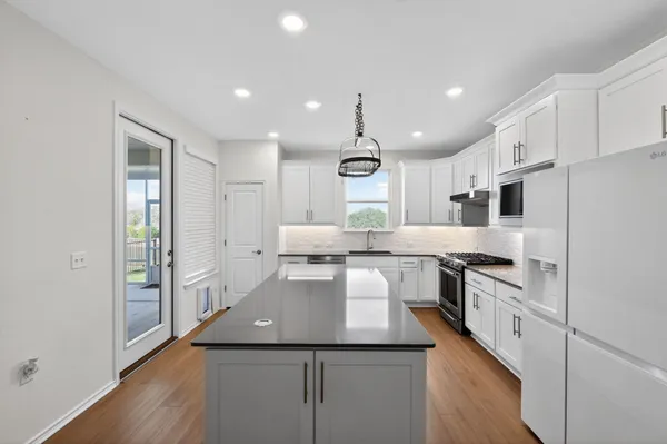 a kitchen with kitchen island a counter top space a sink stainless steel appliances and cabinets