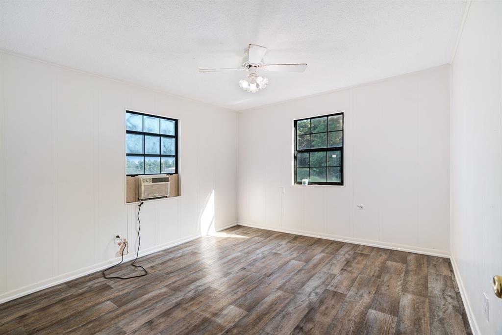 3875 Highway 271 Powderly, TX 75473 - Photo 13 of 25 an empty room with wooden floor chandelier fan and windows