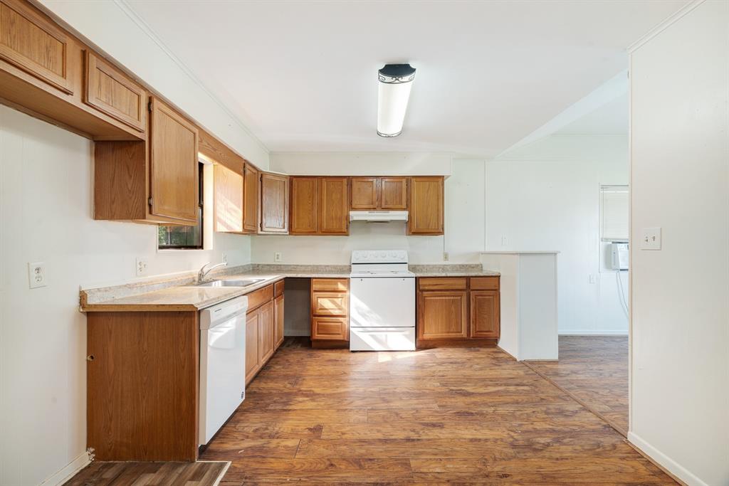 3875 Highway 271 Powderly, TX 75473 - Photo 10 of 25 a kitchen with a sink dishwasher a stove and a refrigerator with wooden floor