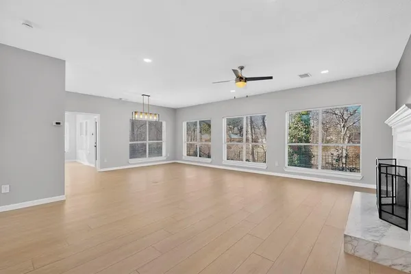 a view of an empty room with a window and wooden floor