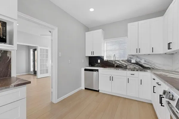 a kitchen with granite countertop white cabinets and white appliances
