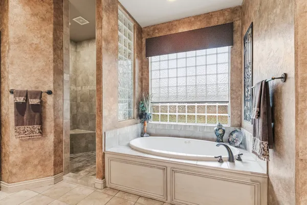 a spacious bathroom with a sink double vanity granite tub shower and a mirror