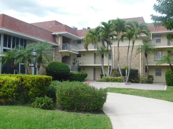 a front view of multi story residential apartment building with yard and green space