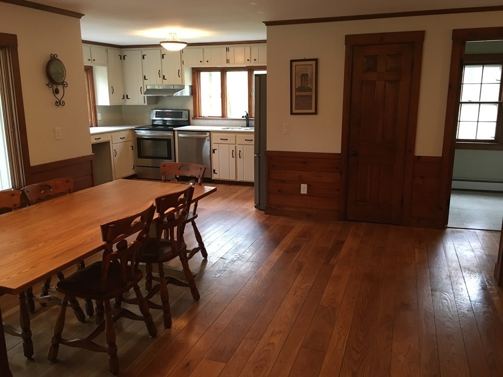 3333 Diamond Hill Road Cumberland, RI 02864 - Photo 10 of 29 a kitchen with stainless steel appliances granite countertop a stove a refrigerator a sink a dining table and chairs with wooden floor