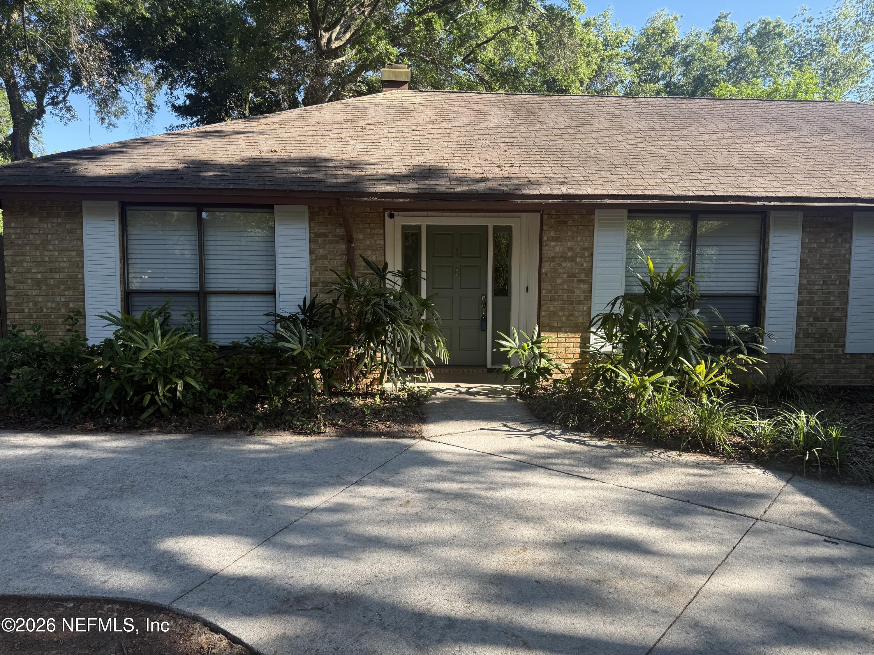 11238 McCormick Road Jacksonville, FL 32225 - Photo 4 of 25 a view of a house with brick walls plants and large tree
