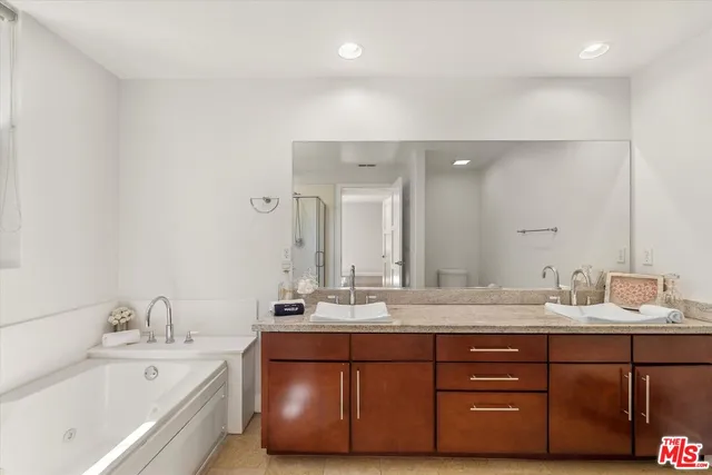 a bathroom with a tub sink double vanity and mirror