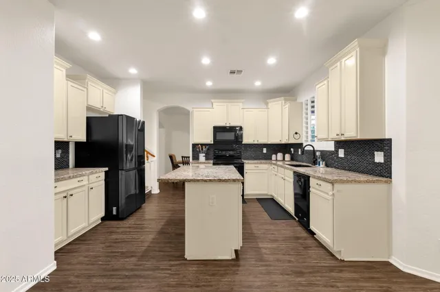 a kitchen with stainless steel appliances granite countertop wooden floors and white cabinets