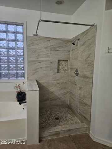 a spacious bathroom with a granite countertop sink a mirror a bathtub and next to a window