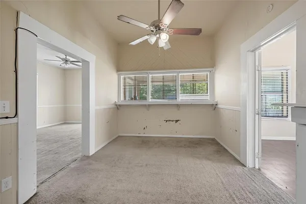 an empty room with chandelier fan and windows