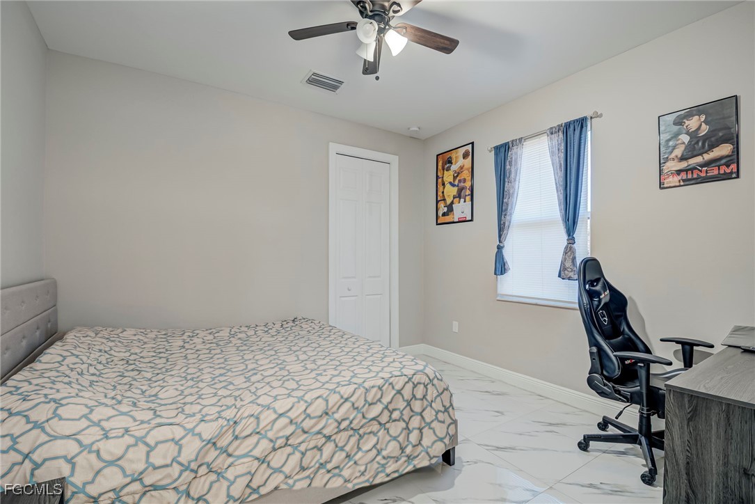3309 30th Street Southwest Lehigh Acres, FL 33976 - Photo 12 of 28 a bedroom with a bed and a chandelier