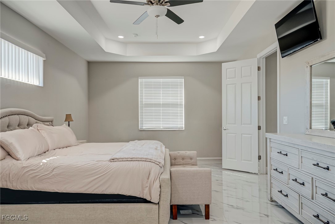 3309 30th Street Southwest Lehigh Acres, FL 33976 - Photo 16 of 28 a bedroom with a bed a couch and a ceiling fan