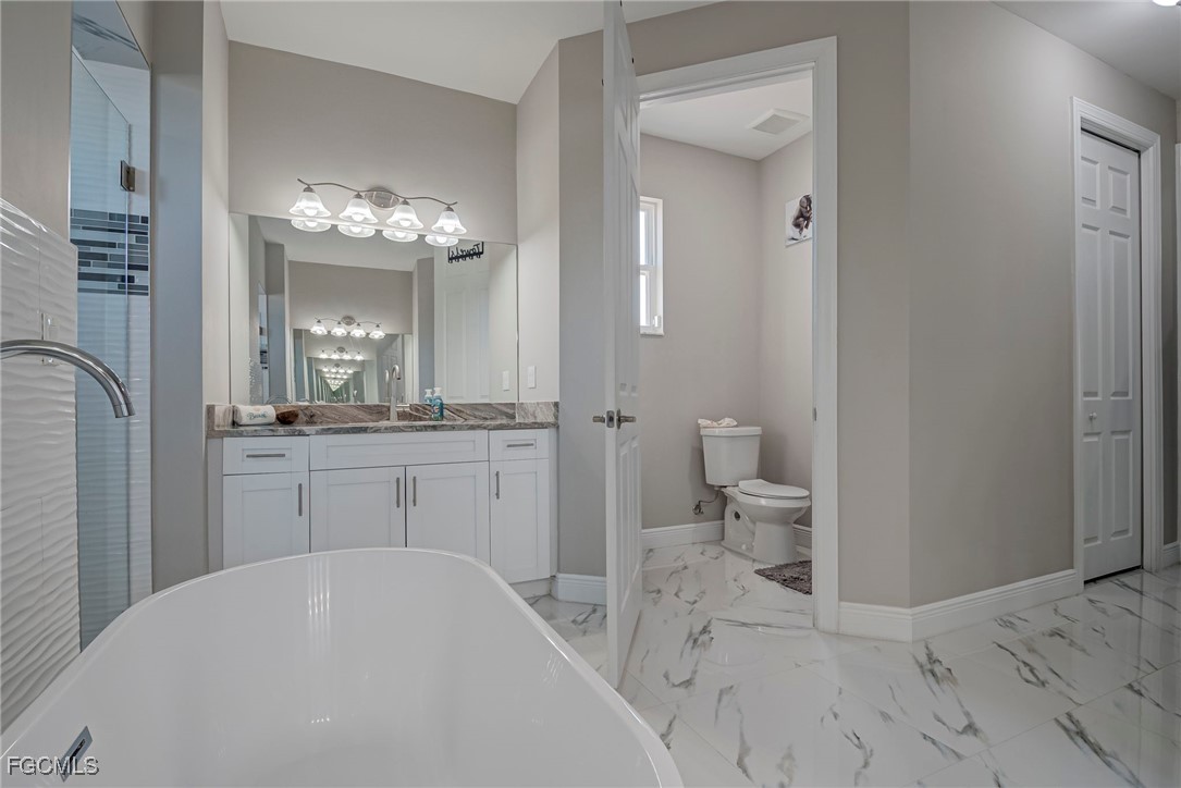3309 30th Street Southwest Lehigh Acres, FL 33976 - Photo 19 of 28 a bathroom with a sink a toilet and a mirror