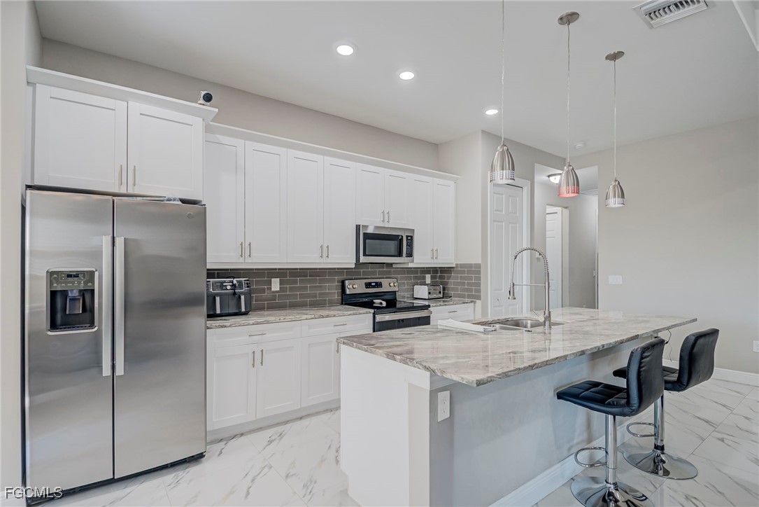3309 30th Street Southwest Lehigh Acres, FL 33976 - Photo 7 of 28 a kitchen with stainless steel appliances a sink stove and refrigerator