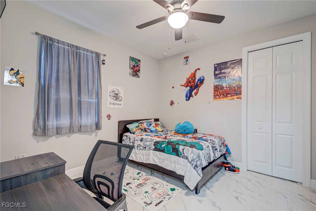 3309 30th Street Southwest Lehigh Acres, FL 33976 - Photo 10 of 28 a bedroom with a bed and a chandelier