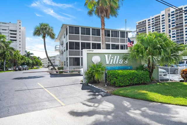 a front view of a building with garden and parking