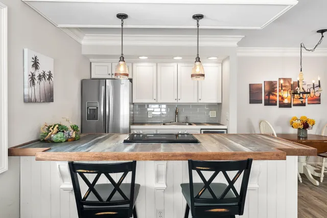 a kitchen with stainless steel appliances granite countertop a dining table chairs and a refrigerator