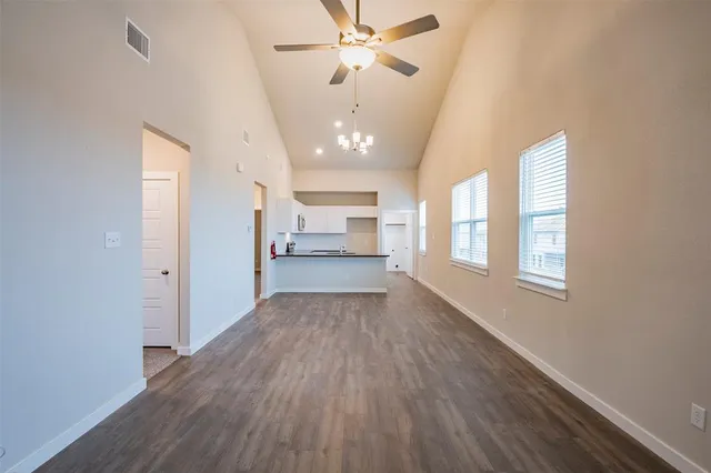 a view of a hallway with wooden floor and a kitchen