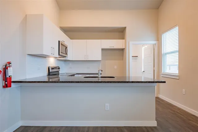 a kitchen with stainless steel appliances granite countertop a sink a stove and a microwave oven on the counter