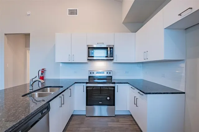 a kitchen with stainless steel appliances granite countertop a sink stove and cabinets
