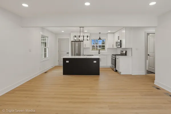 a kitchen with stainless steel appliances a sink a stove a refrigerator a center island and cabinets