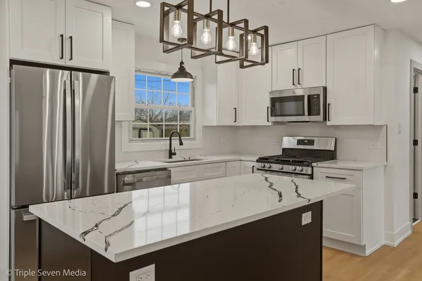 a kitchen with kitchen island granite countertop a stove and a wooden floors