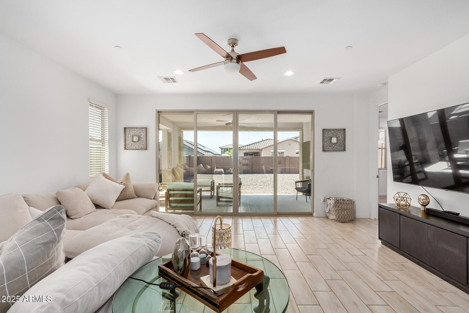 13319 West Red Range Way Peoria, AZ 85383 - Photo 7 of 38 a living room with furniture a ceiling fan a flat screen tv and a large window