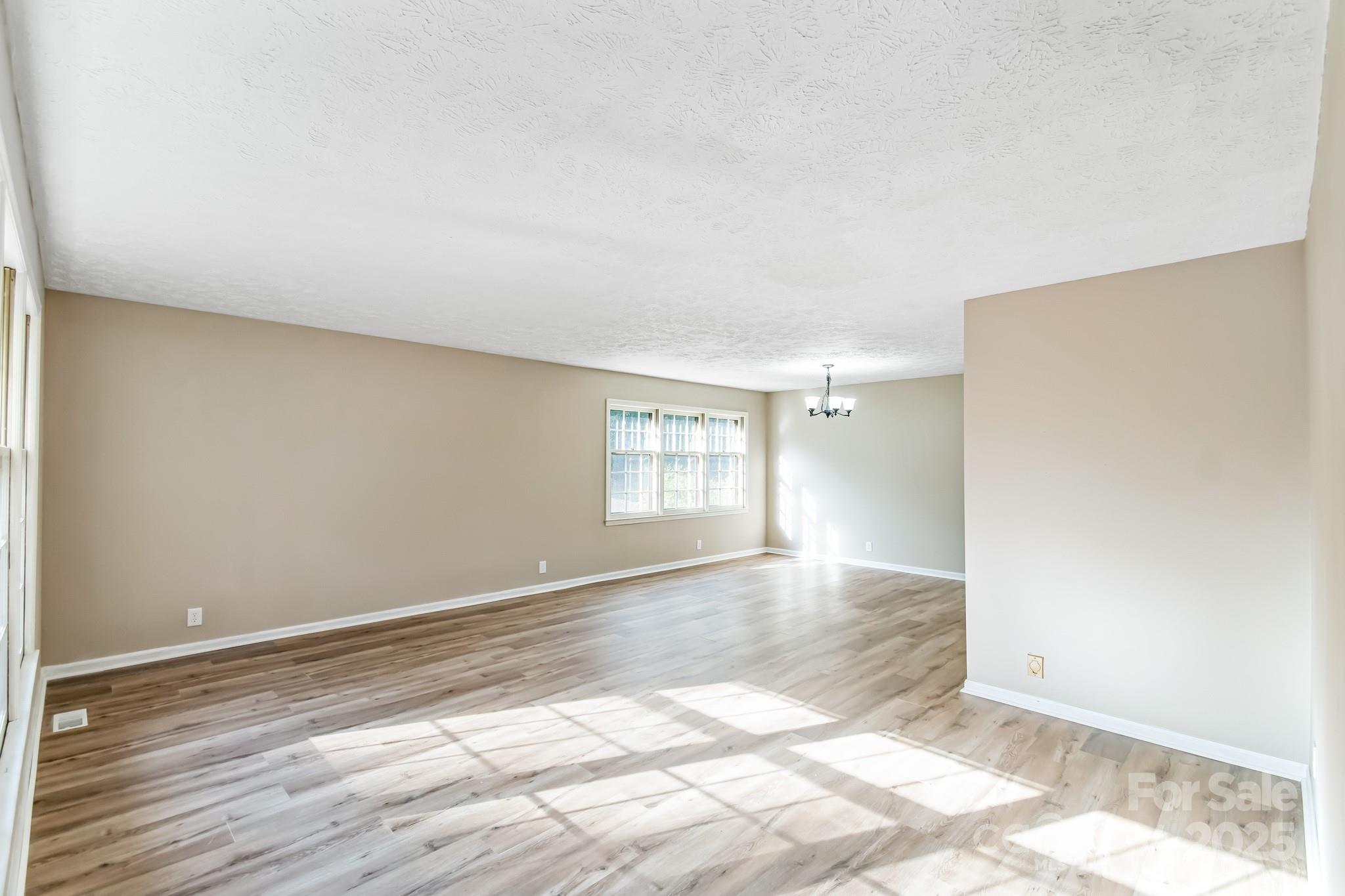 407 Covington Street Rockingham, NC 28379 - Photo 12 of 31 a view of an empty room with wooden floor and a window