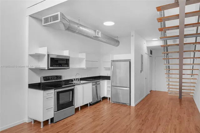a kitchen with granite countertop a refrigerator and a stove top oven