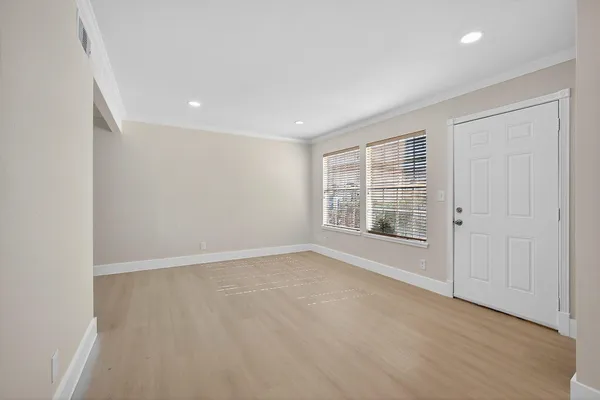 an empty room with wooden floor and windows