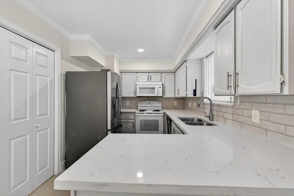 a kitchen with stainless steel appliances a refrigerator a sink a stove and white cabinets