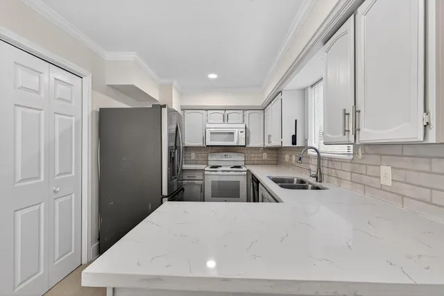 a kitchen with stainless steel appliances a refrigerator a sink a stove and white cabinets