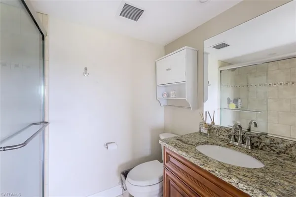 a bathroom with a granite countertop sink a toilet and a mirror