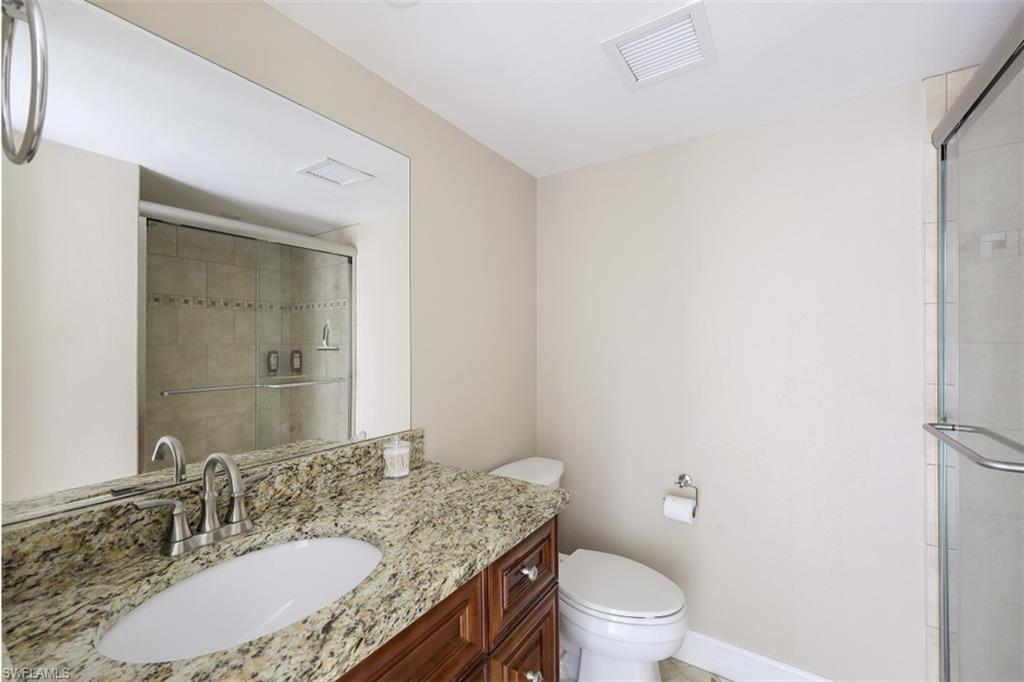 190 Pebble Beach Boulevard, Unit 502 Naples, FL 34113 - Photo 14 of 21 a bathroom with a granite countertop sink a toilet and a mirror