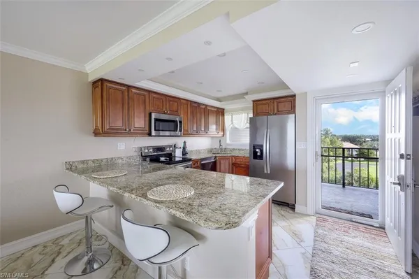 a kitchen with sink a refrigerator and chairs
