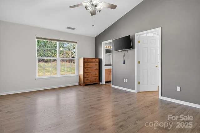an empty room with chandelier fan and windows