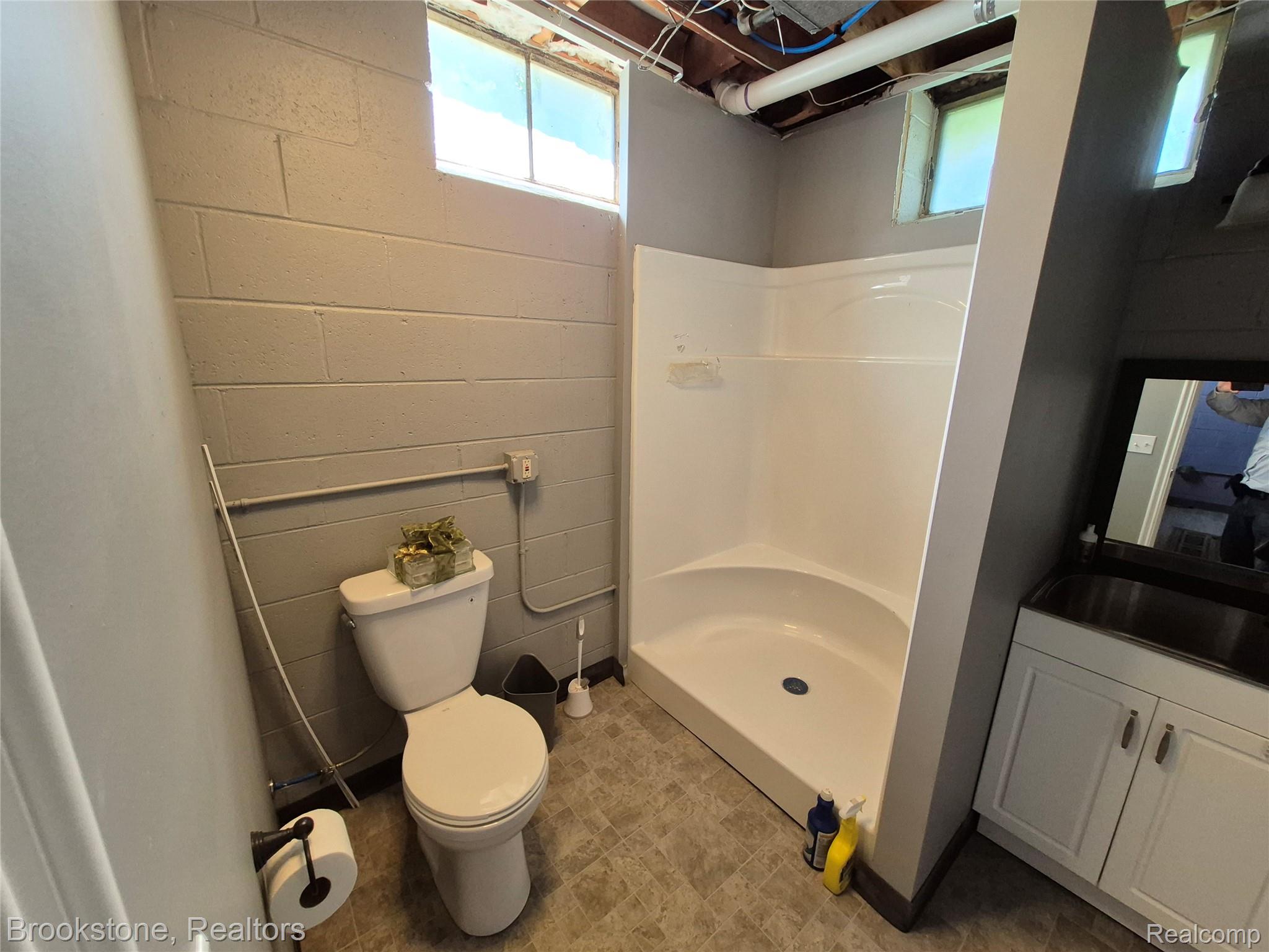 4295 Sashabaw Road Waterford, MI 48329 - Photo 33 of 37 Bathroom featuring a single-piece shower stall, white toilet, and a vanity with a dark countertop and white cabinetry
