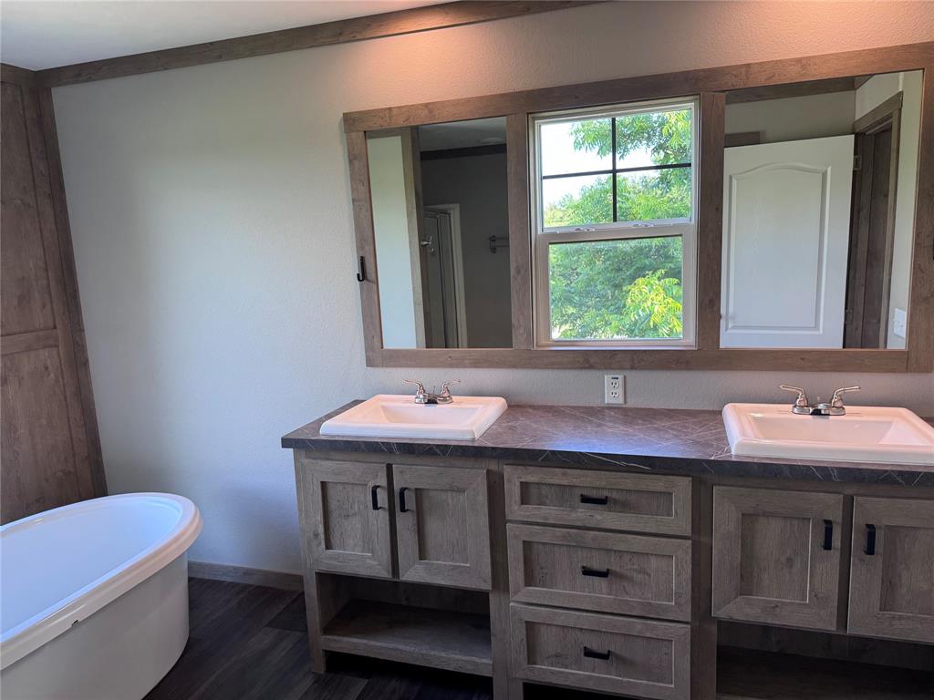 7268 Brangus Road Anna, TX 75409 - Photo 16 of 21 Double vanity with wood-finish cabinetry, integrated sinks, and dark countertops