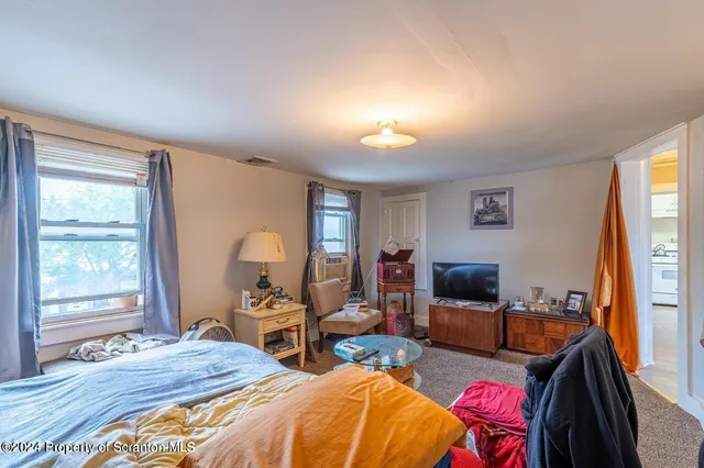 a bedroom with bed a flat tv screen and a dresser
