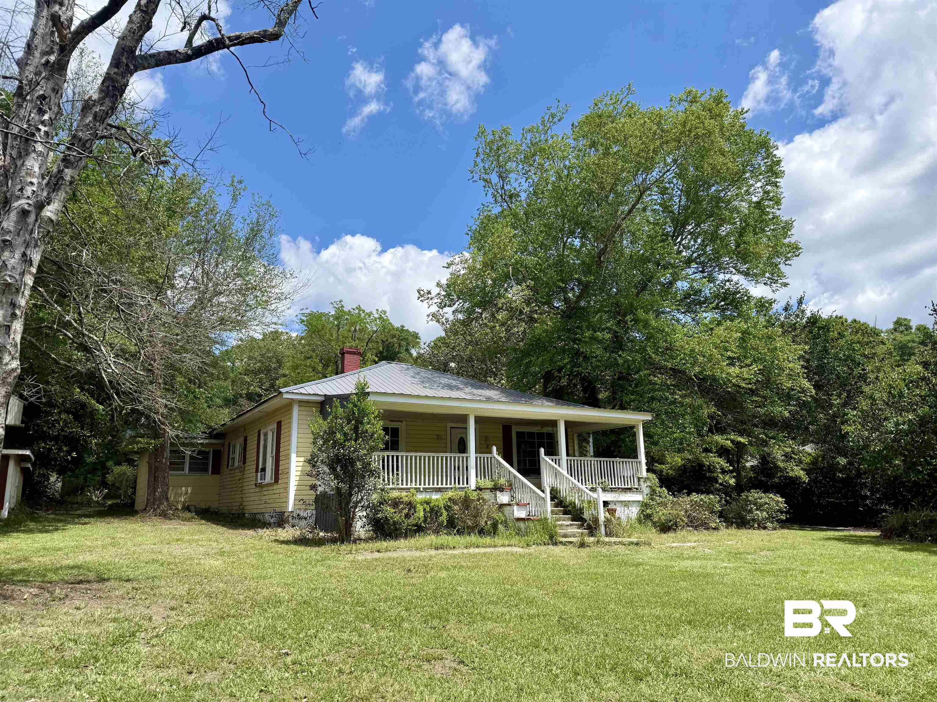 610 Alco Drive Brewton, AL 36426 - Photo 1 of 18 View of front of property with covered porch, a front yard, a chimney, and metal roof