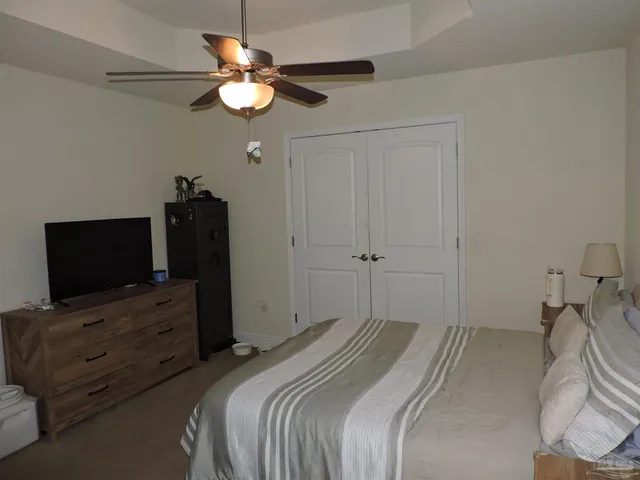 a bedroom with a bed and a flat tv screen on the dresser
