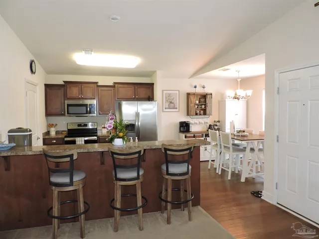 a kitchen with a refrigerator a stove top oven a sink dishwasher and white cabinets with wooden floor