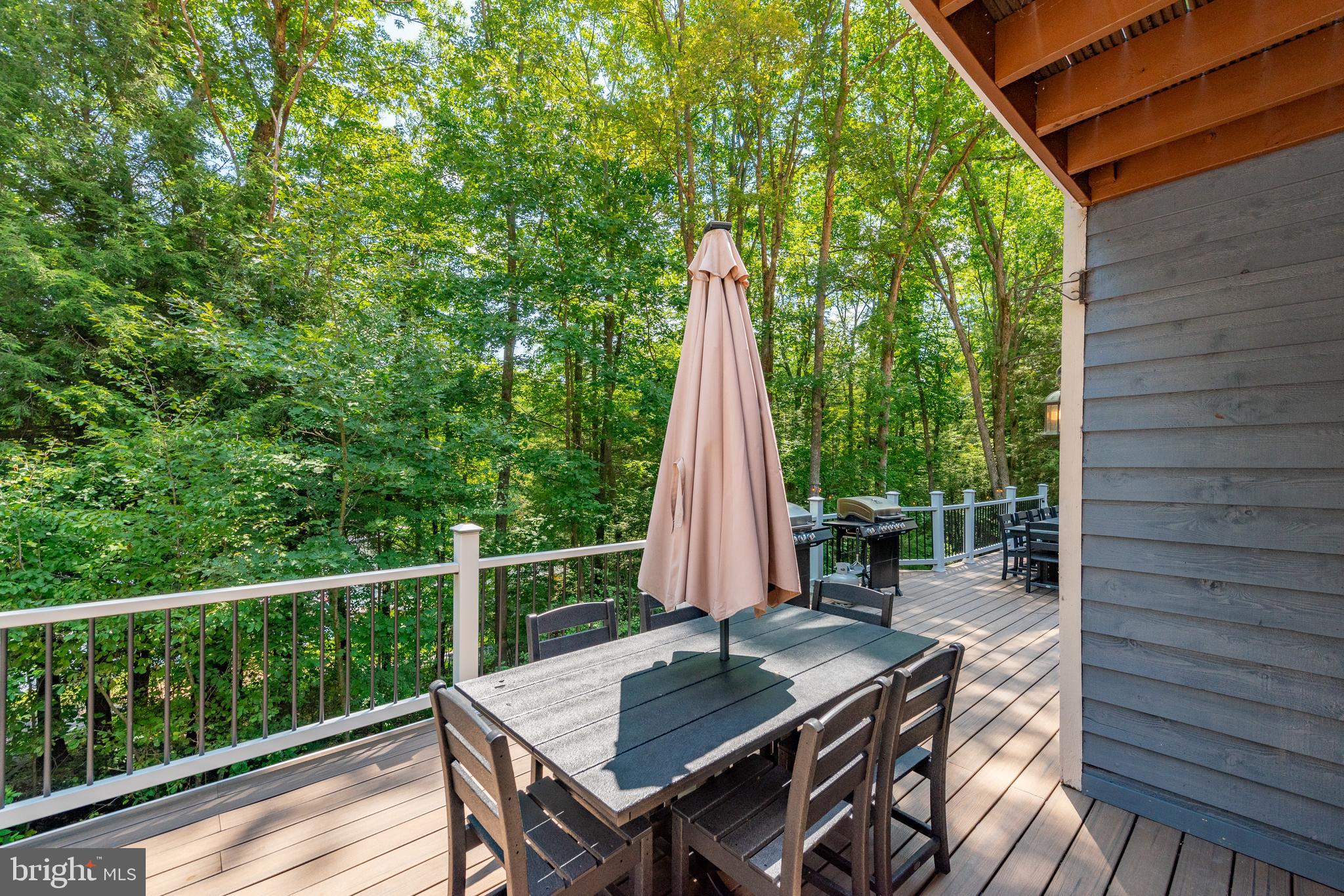 2463 Mayhew Inn Road Oakland, MD 21550 - Photo 134 of 144 a view of a deck with a table and chairs a barbeque with wooden floor and fence